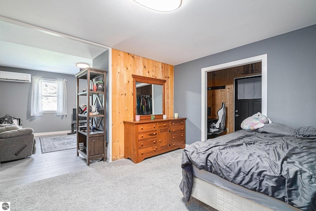 bedroom featuring an AC wall unit, wood walls, and hardwood / wood-style flooring