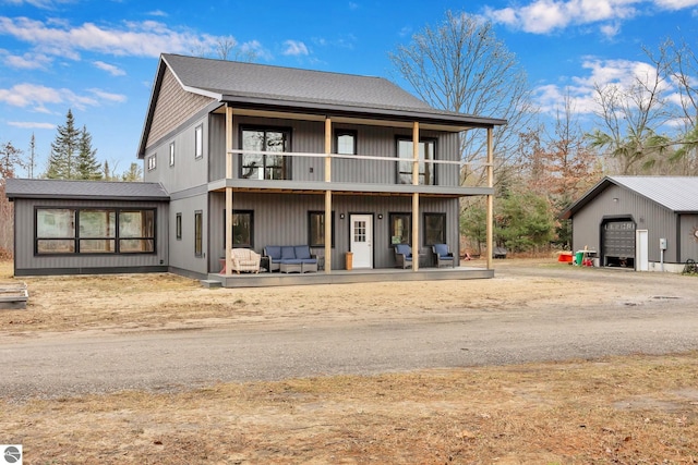 rear view of house featuring a balcony, a garage, and an outdoor structure