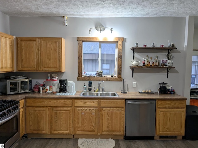 kitchen with a textured ceiling, dark hardwood / wood-style floors, sink, and appliances with stainless steel finishes