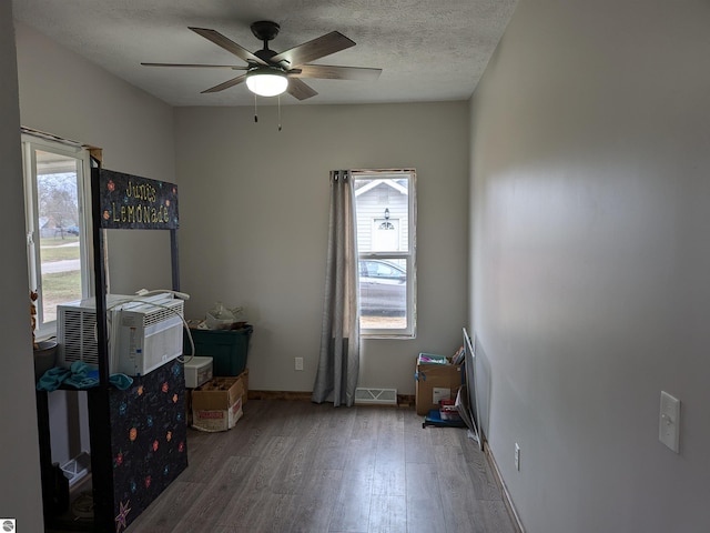 misc room with ceiling fan, a healthy amount of sunlight, a textured ceiling, and hardwood / wood-style flooring