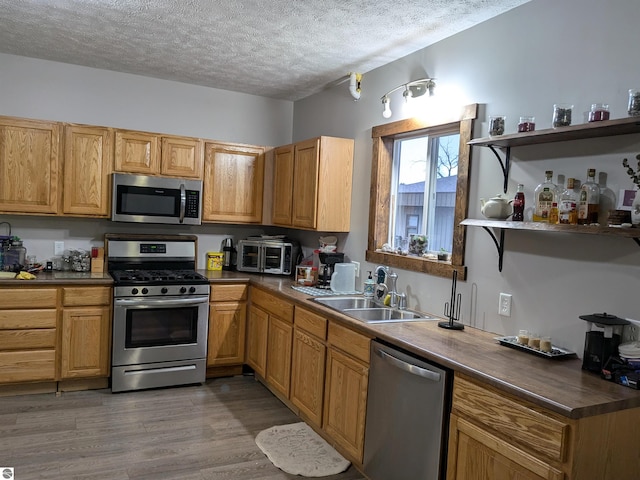 kitchen featuring hardwood / wood-style flooring, sink, stainless steel appliances, and a textured ceiling