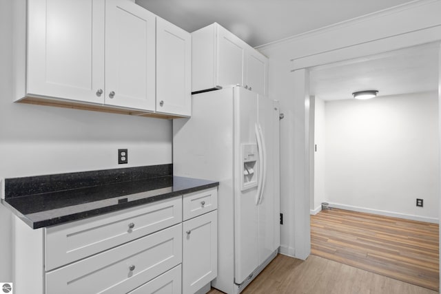 kitchen with white refrigerator with ice dispenser, light hardwood / wood-style flooring, white cabinetry, and dark stone countertops