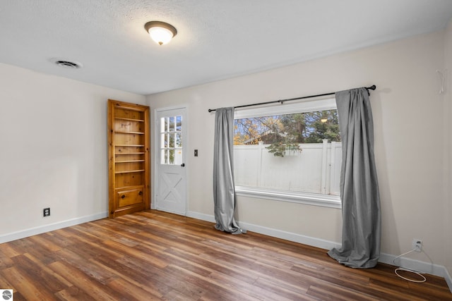 empty room featuring wood-type flooring and a textured ceiling