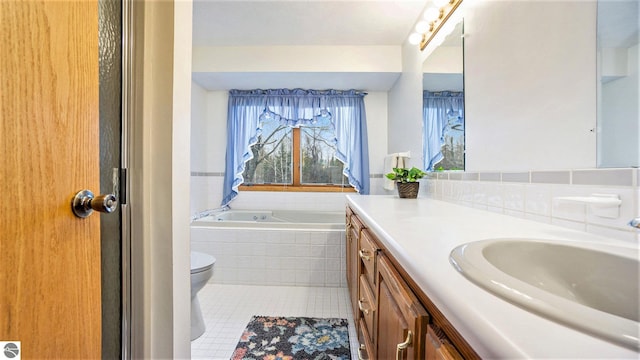 bathroom with toilet, vanity, a relaxing tiled tub, and tile patterned floors