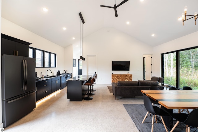 dining room featuring high vaulted ceiling, ceiling fan with notable chandelier, sink, and a wealth of natural light