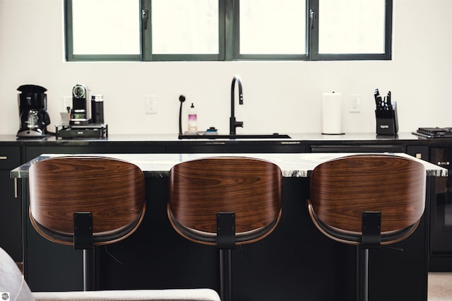 bar featuring light stone counters, a healthy amount of sunlight, and sink