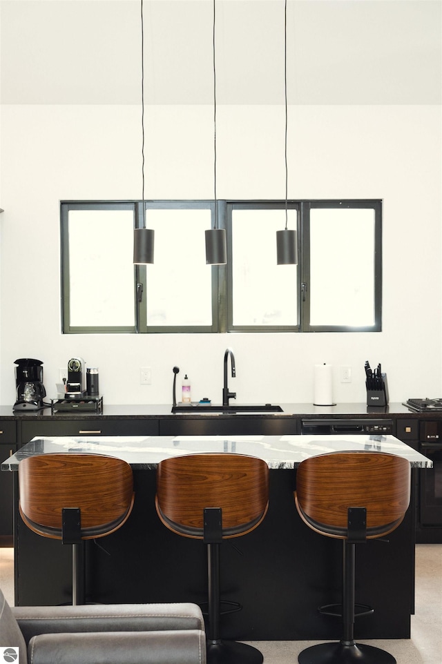 bar featuring dark stone counters, sink, and pendant lighting