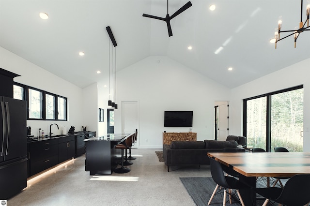 dining room with high vaulted ceiling, sink, ceiling fan with notable chandelier, and a wealth of natural light