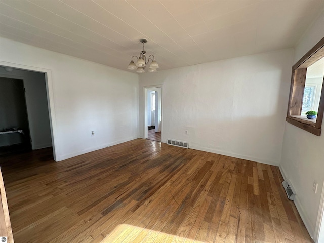 unfurnished room with a chandelier and dark hardwood / wood-style floors