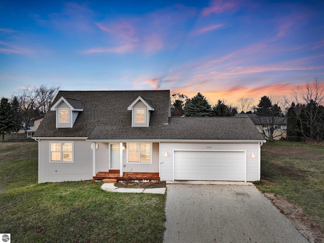 cape cod house featuring a garage and a yard