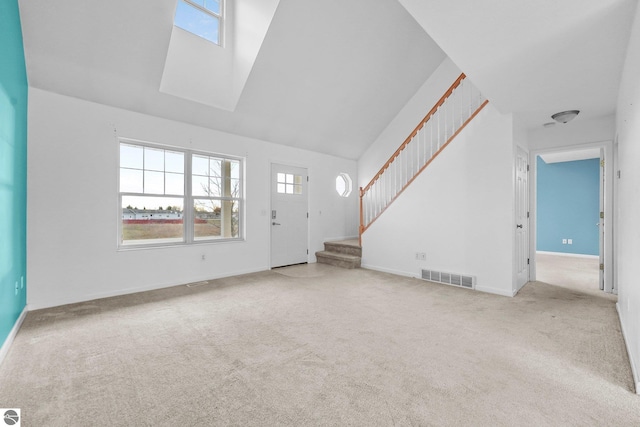 unfurnished living room featuring light colored carpet, high vaulted ceiling, and a skylight