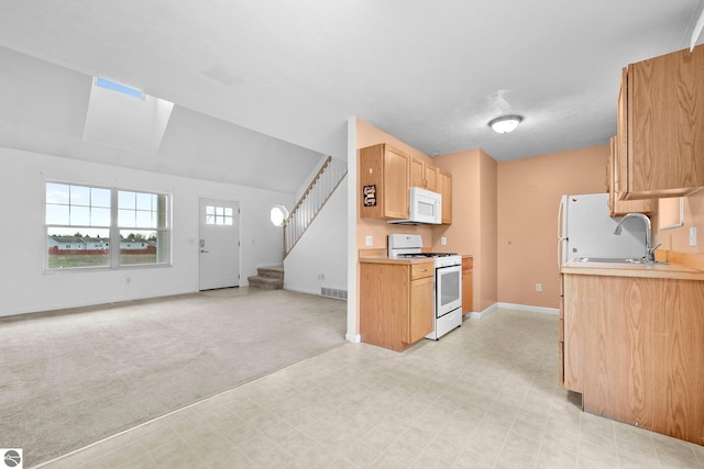 kitchen featuring a skylight, sink, light colored carpet, and white appliances