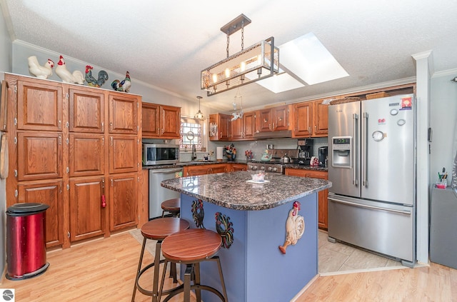 kitchen with a center island, light hardwood / wood-style flooring, hanging light fixtures, and appliances with stainless steel finishes