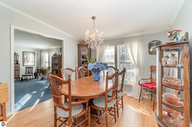 dining area with an inviting chandelier, crown molding, a textured ceiling, and light hardwood / wood-style flooring