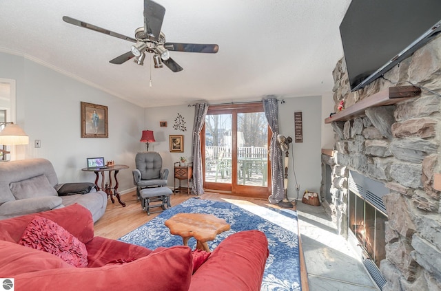 living room featuring ceiling fan, a stone fireplace, crown molding, a textured ceiling, and light wood-type flooring