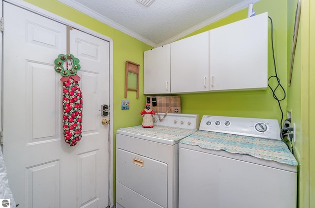 washroom with washing machine and clothes dryer, cabinets, a textured ceiling, and ornamental molding