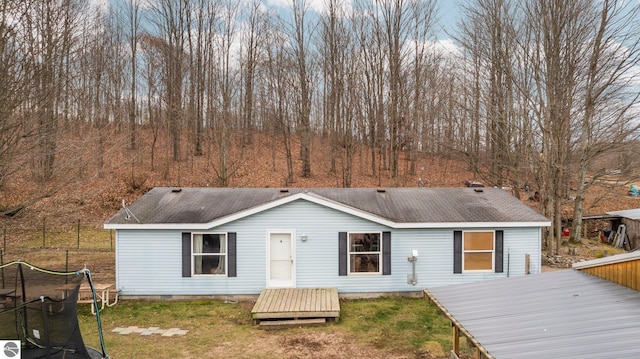 view of front facade featuring a wooden deck, a front yard, and a trampoline