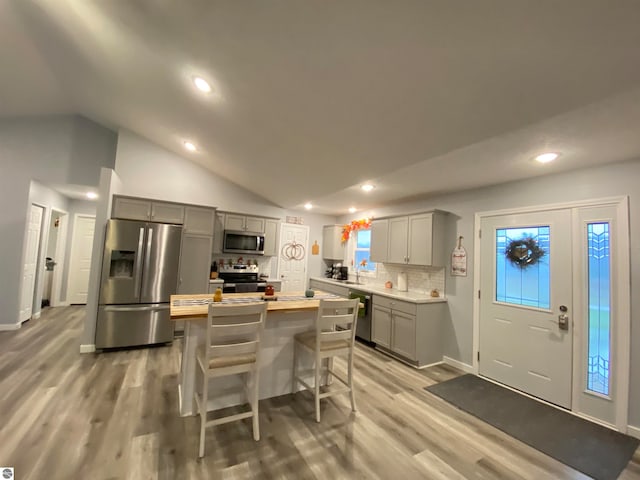 kitchen with wood counters, light wood-type flooring, gray cabinetry, stainless steel appliances, and lofted ceiling