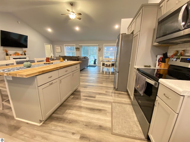 kitchen featuring a center island, wood counters, light hardwood / wood-style floors, lofted ceiling, and appliances with stainless steel finishes