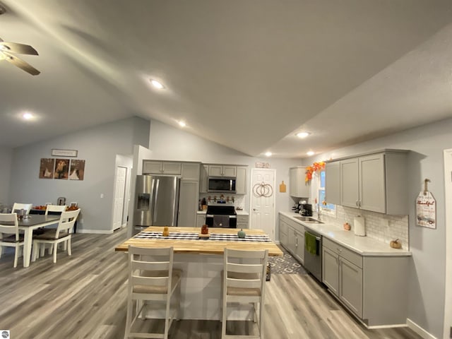 kitchen with butcher block counters, gray cabinetry, light hardwood / wood-style flooring, lofted ceiling, and appliances with stainless steel finishes