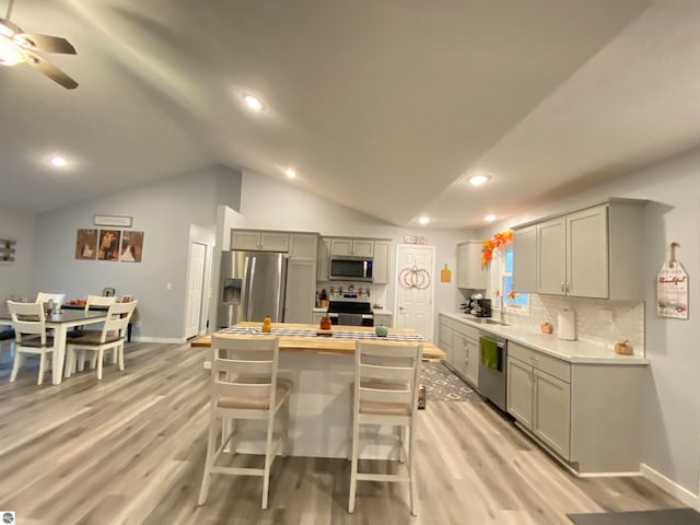 kitchen with gray cabinetry, sink, lofted ceiling, and appliances with stainless steel finishes