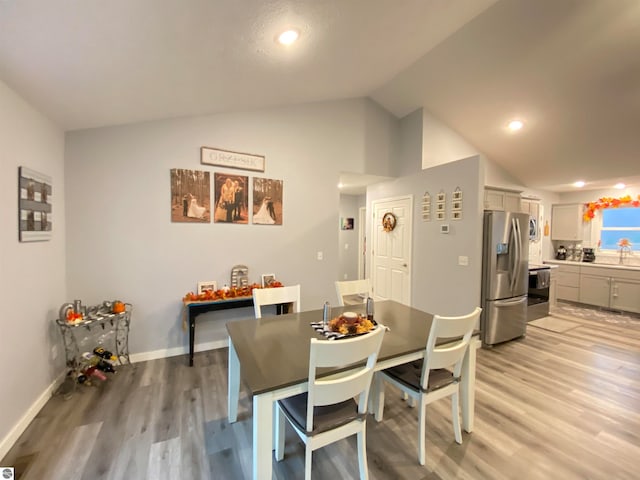 dining area featuring sink, light hardwood / wood-style floors, and lofted ceiling