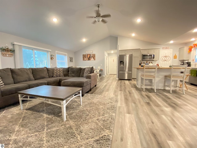 living room with ceiling fan, light wood-type flooring, and lofted ceiling