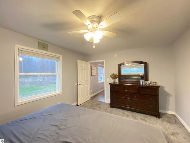 bedroom with multiple windows, ceiling fan, and light carpet