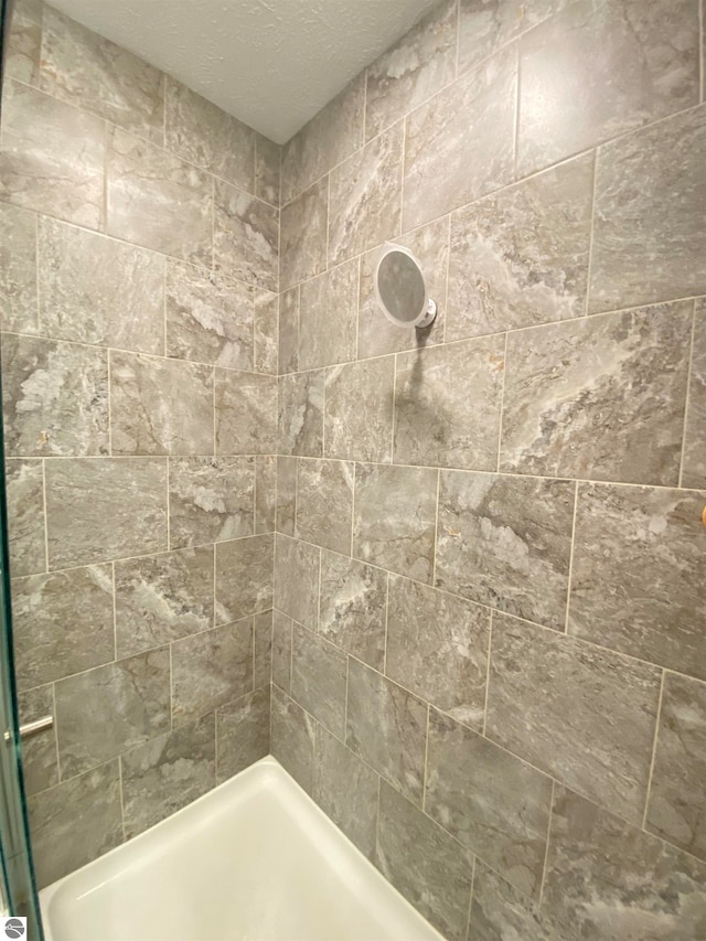 bathroom featuring a tile shower and a textured ceiling