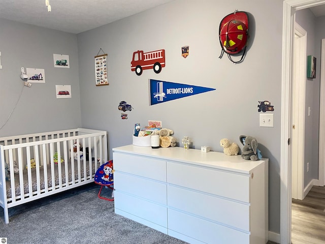 bedroom featuring wood-type flooring, a textured ceiling, and a nursery area