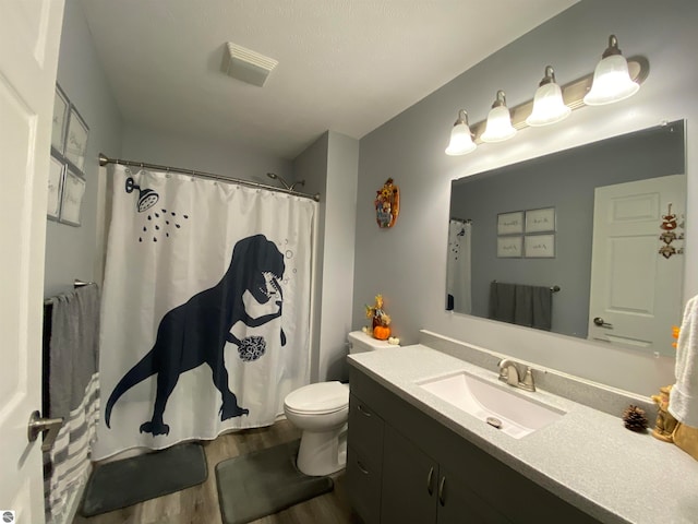 bathroom with hardwood / wood-style floors, vanity, toilet, and walk in shower