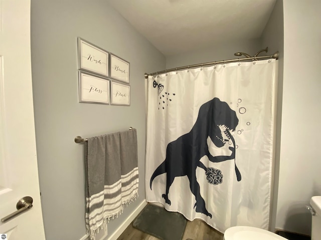 bathroom featuring hardwood / wood-style flooring, a shower with curtain, and toilet