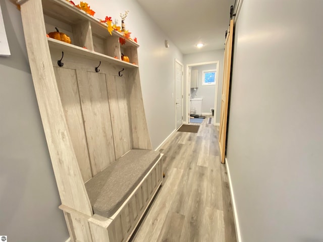 mudroom with a barn door and light hardwood / wood-style flooring