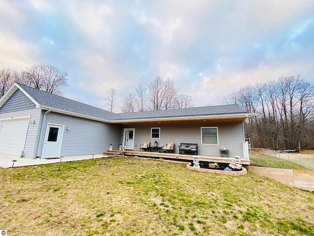 rear view of property with a yard, a garage, and a wooden deck