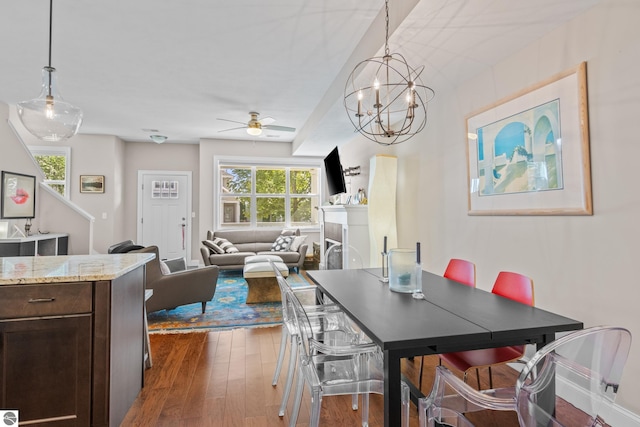 dining area featuring ceiling fan with notable chandelier and dark hardwood / wood-style flooring