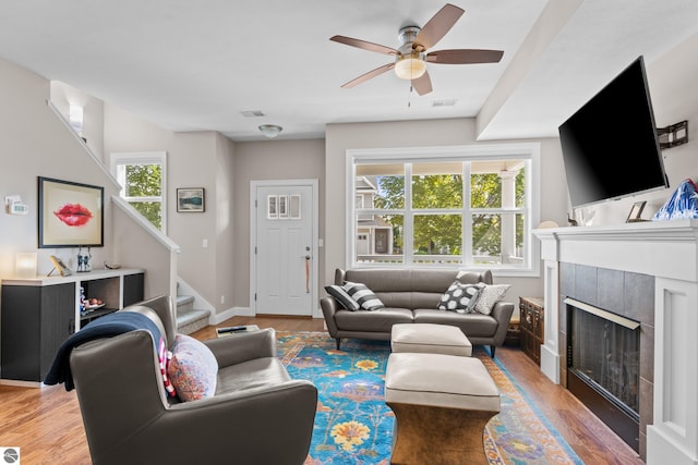 living room with ceiling fan, hardwood / wood-style flooring, plenty of natural light, and a tiled fireplace