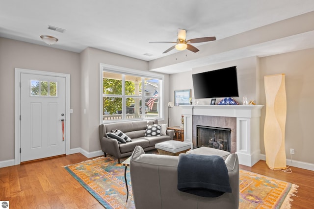 living room with ceiling fan, light wood-type flooring, and a fireplace