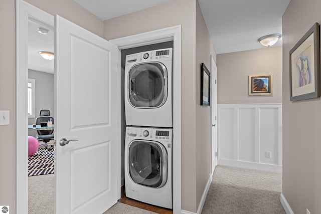 clothes washing area with light colored carpet and stacked washing maching and dryer