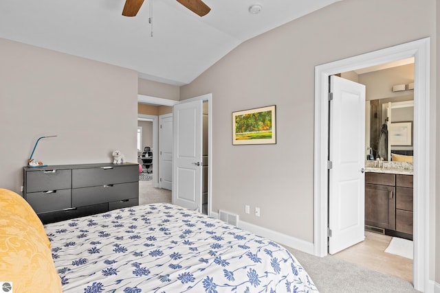 bedroom featuring light carpet, connected bathroom, vaulted ceiling, and ceiling fan