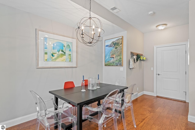 dining room with hardwood / wood-style floors and an inviting chandelier