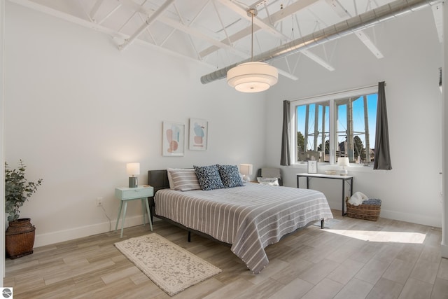 bedroom featuring beam ceiling, high vaulted ceiling, and light wood-type flooring