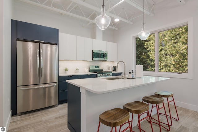 kitchen featuring a breakfast bar, a kitchen island with sink, tasteful backsplash, decorative light fixtures, and stainless steel appliances