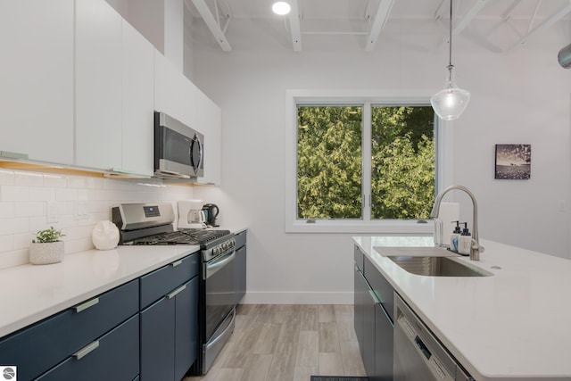 kitchen with white cabinetry, sink, decorative light fixtures, and appliances with stainless steel finishes