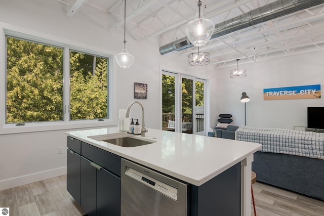 kitchen featuring dishwasher, sink, decorative light fixtures, a center island with sink, and light wood-type flooring