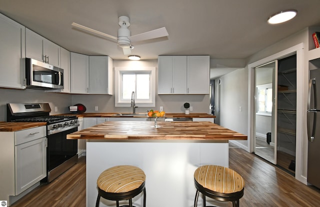 kitchen with wood counters, appliances with stainless steel finishes, a center island, and white cabinets