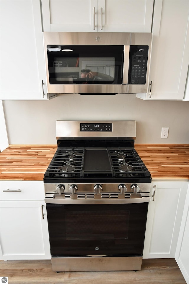 kitchen featuring white cabinets, butcher block counters, appliances with stainless steel finishes, and light hardwood / wood-style flooring