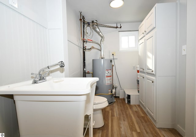 bathroom with toilet, gas water heater, and hardwood / wood-style flooring