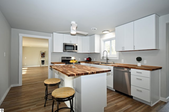 kitchen featuring a center island, a kitchen breakfast bar, sink, butcher block countertops, and stainless steel appliances