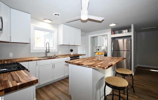 kitchen with stainless steel refrigerator, sink, white cabinets, and wood counters