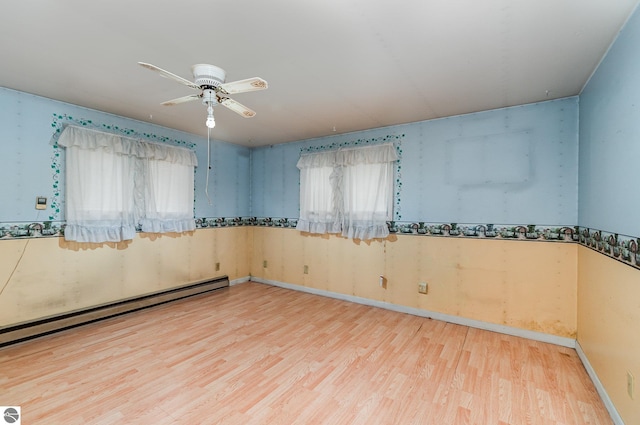 unfurnished room featuring baseboard heating, a wealth of natural light, and light hardwood / wood-style flooring